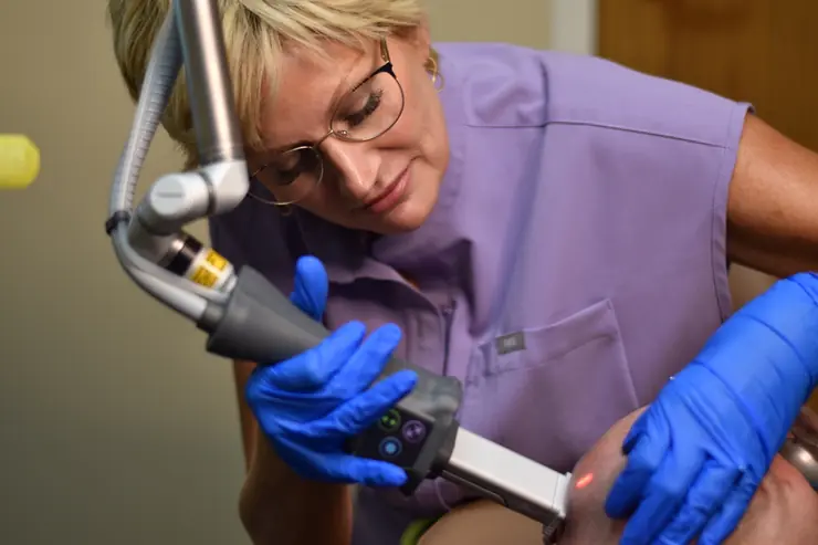 Close-up of Haley performing a laser treatment using protective gloves